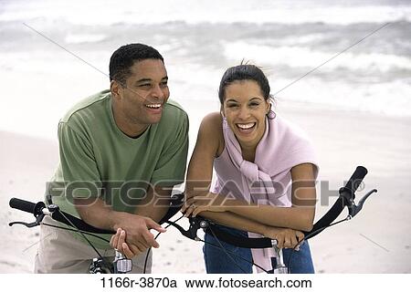 Stock Image - people, couple, beach, riding, bicycles, cycling, ride. Fotosearch