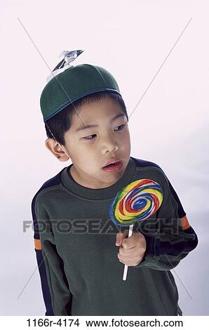 Picture - people, eating, hat, Asian, candy, boy, child. Fotosearch