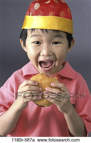 Stock Image - people, eating, hat, Asian, hamburger, boy, child. Fotosearch