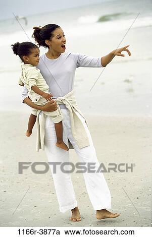 Stock Image - people, mother, beach, pointing, point, looking, carrying. Fotosearch