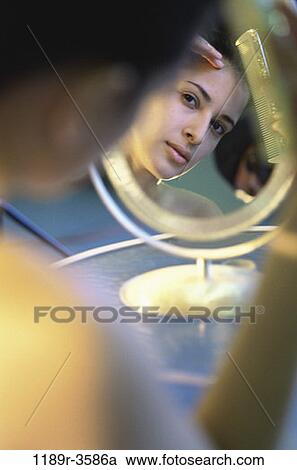 Stock Image - people, reflection, woman, Hispanic, mirror, beauty, combing. Fotosearch