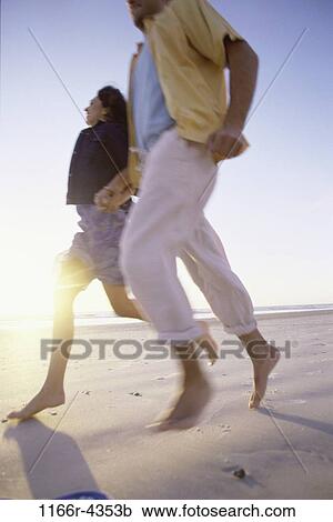 Stock Image - people, running, couple, beach, brunette, clothed, Caucasian. Fotosearch