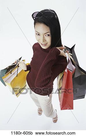 Stock Image - people, woman, Asian, carrying, shopping, shop, bags. Fotosearch