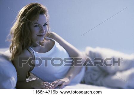 Stock Image - people, woman, bed, laying, brunette, indoors, Caucasian. Fotosearch