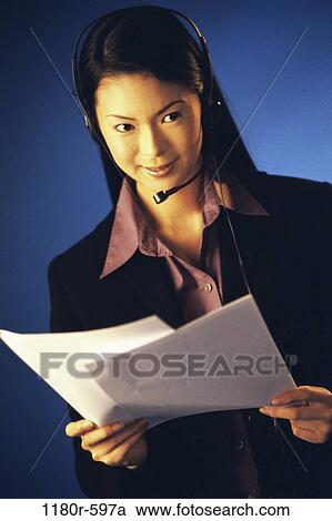 Stock Image - people, woman, headset, talking, Asian, papers, holding. Fotosearch