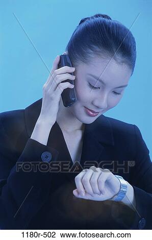 Stock Image - woman, talking, Asian, phone, watch, business, cell phone. Fotosearch