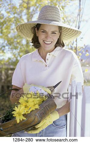 Stock Image - fence, people, woman, daisies, flowers, gardening, basket. Fotosearch