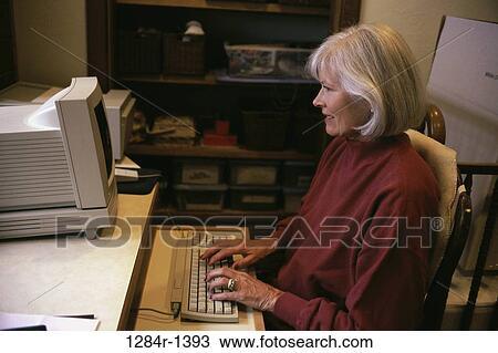 Stock Image - people, home, woman, senior, computer, typing. Fotosearch