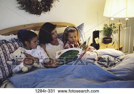 Stock Image - people, mother, reading, bed, stuffed animal, family, toy. Fotosearch