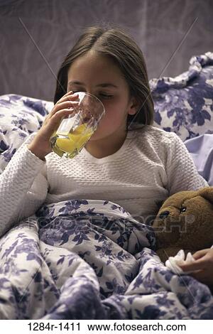 Stock Image - people, orange juice, bed, drinking, stuffed animal, girl, cold. Fotosearch