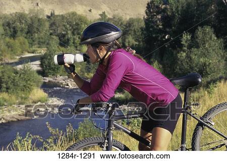 Stock Image - people, woman, bicycle, helmet, drinking, outdoors. Fotosearch