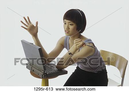 Stock Image - people, woman, headset, Asian, computer, laptop, phone. Fotosearch