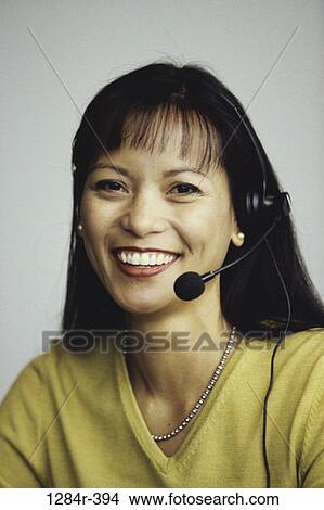 Picture - woman, telephone, talking, Asian, phone, business, headphone. Fotosearch