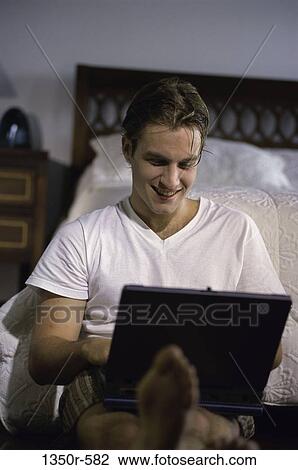 Stock Image - people, computer, laptop, bed, bedroom. Fotosearch