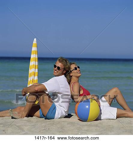 Picture - sand, people, umbrella, couple, ocean, sitting, ball. Fotosearch