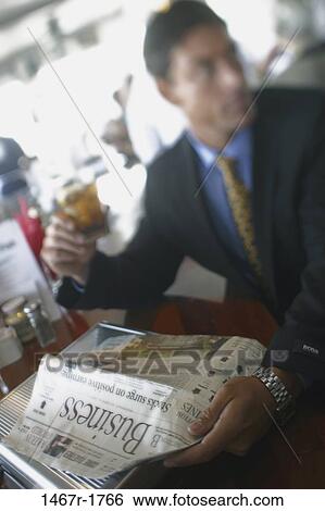 Stock Photograph - blur, newspaper, Hispanic, reading, drinking, individual, cafe. Fotosearch