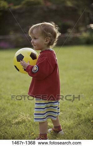 Stock Photo - people, ball, toddler, boy, standing, outdoors, carrying. Fotosearch