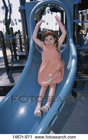 Stock Image - people, smiling, Hispanic, girl, sliding, playground, outdoors. Fotosearch