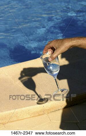 Stock Photo - hand, glass, wine, holding, poolside, relaxing, alcoholic. Fotosearch
