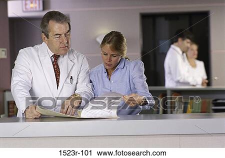 Stock Image - talking, paperwork, discussion, conversation, doctor, nurse. Fotosearch