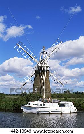 Stock Image - Boat moored near a traditional windmill, River Ant, Norfolk Broads, Norfolk, England. Fotosearch