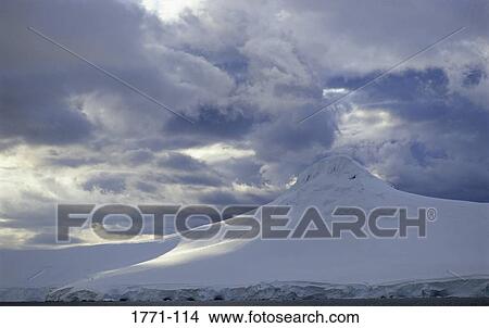 Picture - Clouds over a snow covered mountain, Paradise Bay, Antarctic Peninsula, Antarctica. Fotosearch