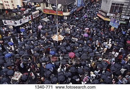 Crowd sheltering under umbrellas at a town square during rainy season, Kerala, India View Large Photo Image Stock Image - Crowd sheltering under umbrellas at a town square during rainy season, Kerala, India. Fotosearch