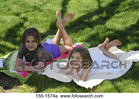 High angle view of two girls lying in grass View Large Photo Image Stock Image - High angle view of two girls lying in grass. Fotosearch