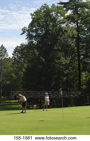Stock Image - Mature couple playing golf. Fotosearch