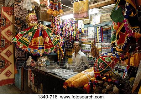 Mature man selling temple umbrellas and clothing used to decorate temple chariot at a market stall, Sri Meenakshi Hindu Temple, Madurai, Tamil Nadu, India View Large Photo Image Stock Photograph - Mature man selling temple umbrellas and clothing used to decorate temple chariot at a market stall, Sri Meenakshi Hindu Temple, Madurai, Tamil Nadu, India. Fotosearch