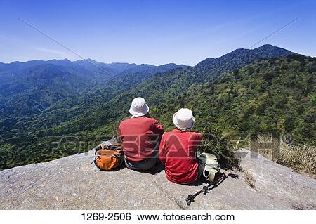 Rear view of a couple sitting on a rock, Taikoiwa, Yakushima Island, Kagoshima Prefecture, Japan View Large Photo Image Stock Photograph - Rear view of a couple sitting on a rock, Taikoiwa, Yakushima Island, Kagoshima Prefecture, Japan. Fotosearch