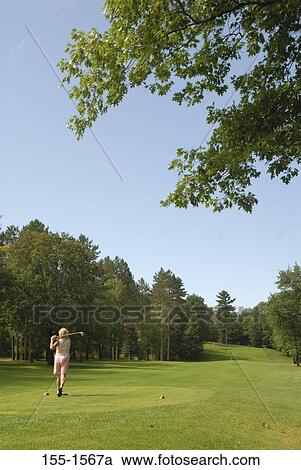 Stock Image - Rear view of a mature woman playing golf. Fotosearch