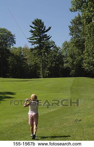 Stock Image - Rear view of a mature woman playing golf. Fotosearch