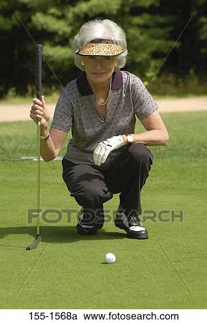 Senior woman lining up a putt on a golf course View Large Photo Image Stock Image - Senior woman lining up a putt on a golf course. Fotosearch
