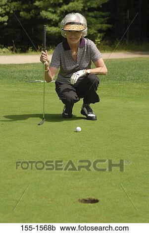 Senior woman lining up a putt on a golf course View Large Photo Image Stock Image - Senior woman lining up a putt on a golf course. Fotosearch