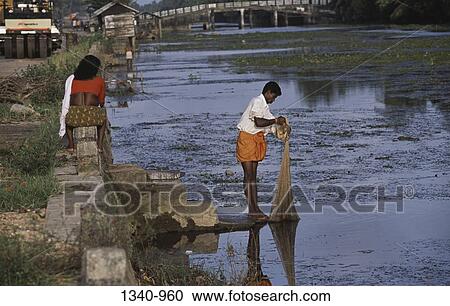 Stock Image - Side profile of a fisherman fishing in a lake, Kerala Backwaters, Kuttanad, Alappuzha District, Kerala, India. Fotosearch