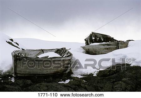 Stock Image - Two broken boats on the frozen rock, Enterprise Island, Antarctic Peninsula, Antarctica. Fotosearch