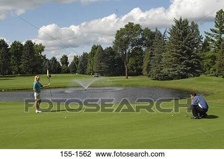 Stock Image - Young couple playing golf. Fotosearch
