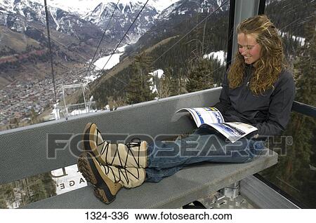 Young woman reading a magazine in an overhead cable car, Telluride, Colorado, USA View Large Photo Image Stock Photograph - Young woman reading a magazine in an overhead cable car, Telluride, Colorado, USA. Fotosearch