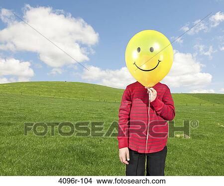 Boy holding a smiley face balloon in front of his face View Large Photo Image Picture - Boy holding a smiley face balloon in front of his face. Fotosearch