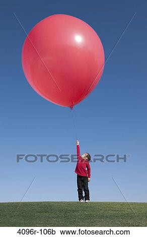 Boy standing with a large balloon View Large Photo Image Stock Image - Boy standing with a large balloon. Fotosearch
