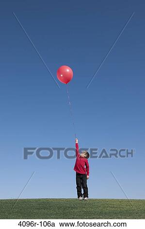 Stock Image - Boy standing with a small balloon. Fotosearch