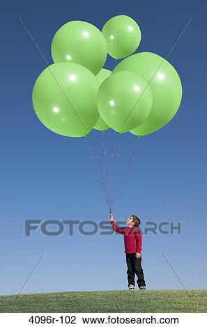 Stock Image - Boy standing with green balloons. Fotosearch