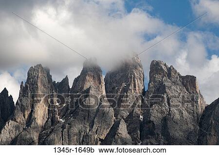 Stock Image - Clouds over mountain range, Geisler Gruppe, Funes Valley, Dolomites, Trentino-Alto-Adige, Italy. Fotosearch