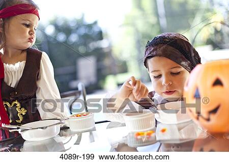 Girls playing Trick Or Treat and eating ice cream View Large Photo Image Stock Photo - Girls playing Trick Or Treat and eating ice cream. Fotosearch