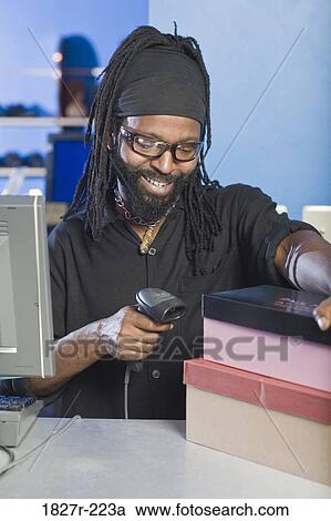 Stock Image - Mid adult man holding bar code reader. Fotosearch