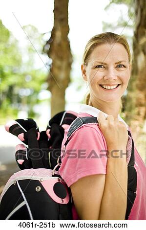Mid adult woman carrying a golf bag View Large Photo Image Stock Image - Mid adult woman carrying a golf bag. Fotosearch