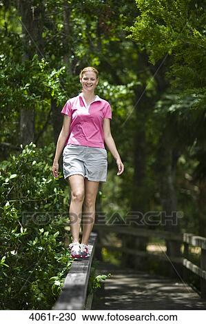 Mid adult woman walking on a railing View Large Photo Image Stock Image - Mid adult woman walking on a railing. Fotosearch