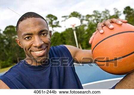 Stock Image - Portrait of a young man holding a basketball. Fotosearch