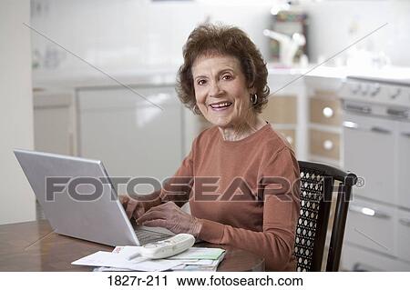 Senior woman working on a laptop and smiling View Large Photo Image Stock Image - Senior woman working on a laptop and smiling. Fotosearch